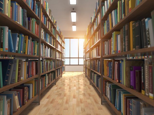 Imagem do corredor de uma biblioteca com estantes de livros