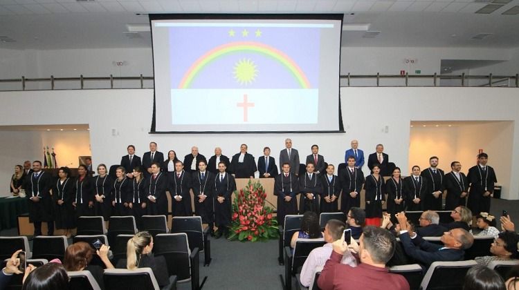 Homens lado a lado no primeiro plano e ao fundo a projeção da bandeira de Pernambuco