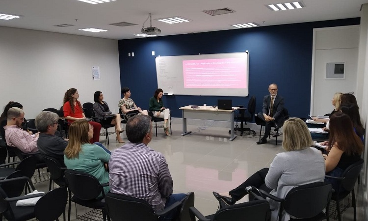 Sala de aula com pessoas em semi-circulo assistindo palestra do juiz Élio Braz