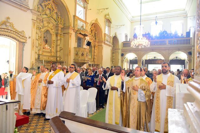 No primeiro plano, padres participam de solenidade em igreja lotada