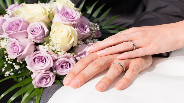 Mãos de um casal segurando um buquê de flores 