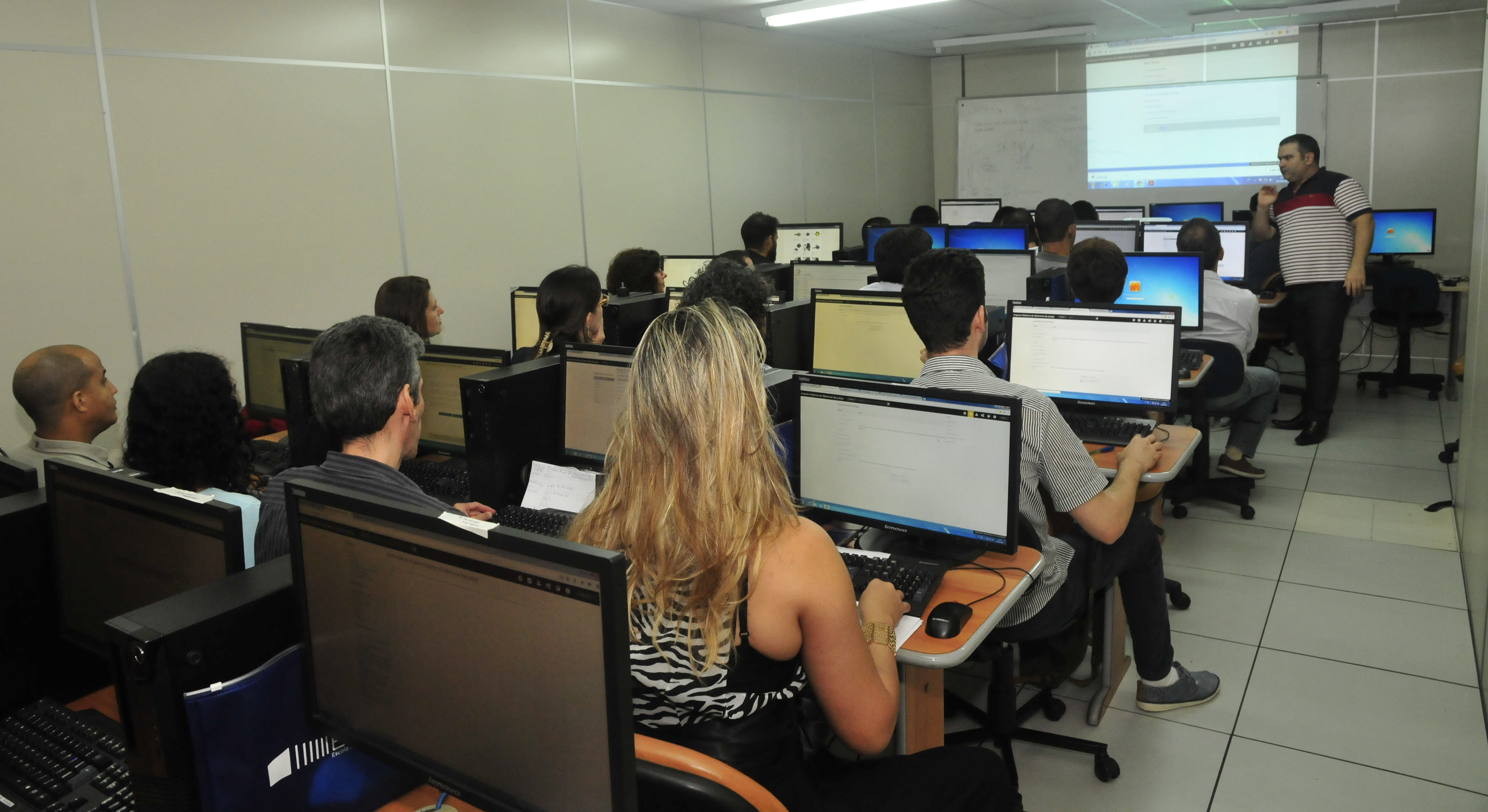 Estudantes em frente a computadores, aprendendo a digitalizar processos