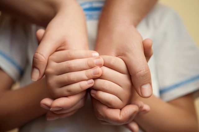 Mãos de adulto seguram mãos de criança