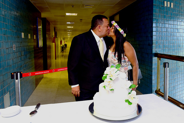 Noivos se beijam em frente perto do bolo de casamento