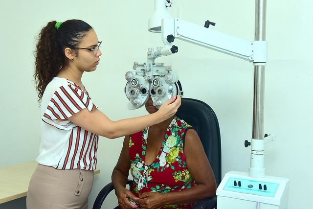 Profissional de saúde ajusta aparelho de oftalmologia em paciente sentada
