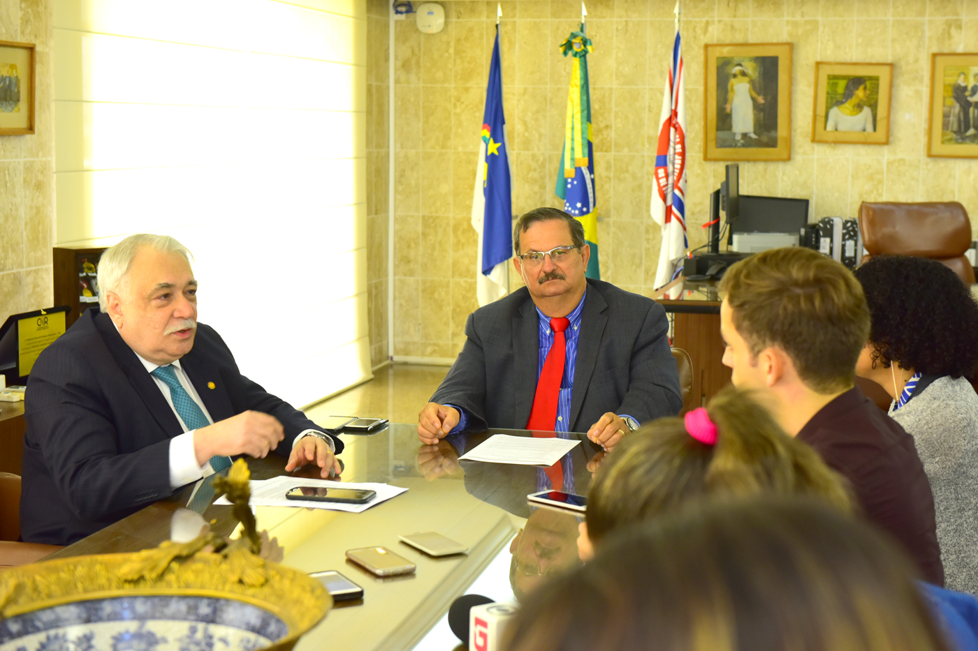 Desembargadores Fernando Cerqueira e Jones Fogueiredo sentados em mesa de reunião, rodeados por jornalistas.