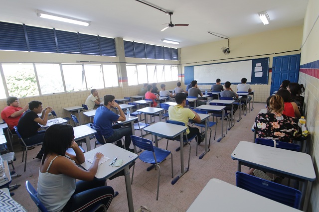 Estudantes sentados em sala de aula aguardam a aplicação da prova