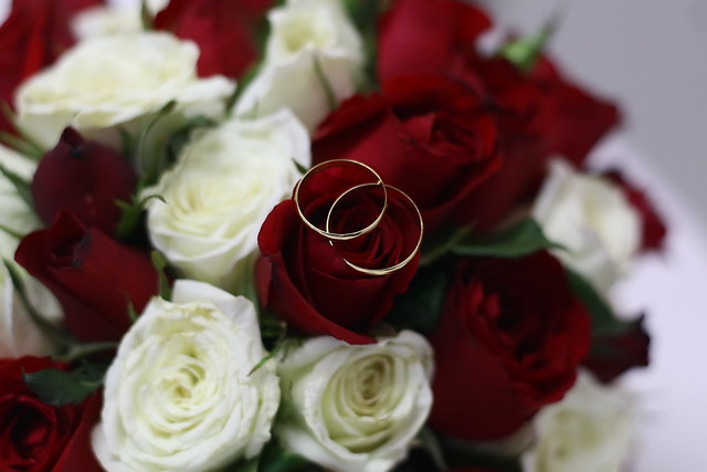 Buquê de rosas brancas e vermelhas com duas alianças douradas em cima