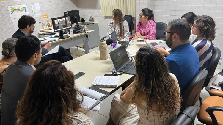Reunião realizada no CIJ com várias instituições para garantir documentação civil a adolescentes socioeducandos. Foto com várias pessoas sentadas em torno de uma mesa retangular.