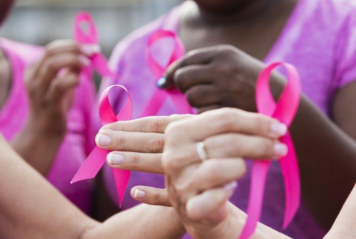 Imagem mostra mãos de mulheres segurando fita cor de rosa que representa a campanha outubro rosa