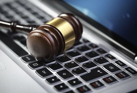 Foto mostra uma martelo de um juiz sob um teclado de laptop, simbolizando a consulta online