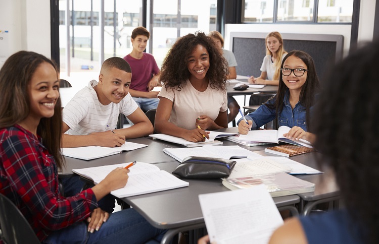 Jovens em volta da mesa, sentados em círculo, estudando 