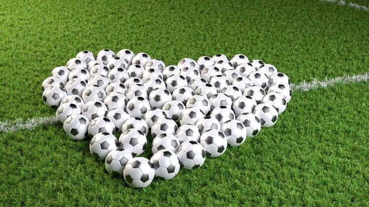Bolas de futebol formando um coração num campo de futebol