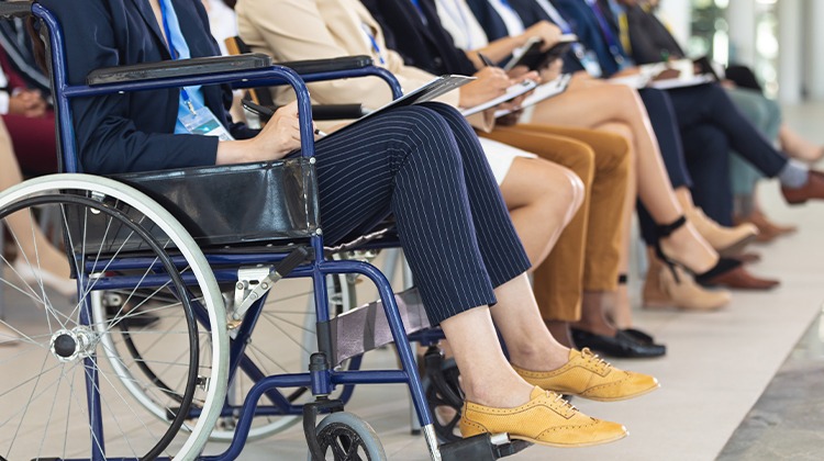 Pernas de pessoas sentadas em fila escrevendo em papéis no colo