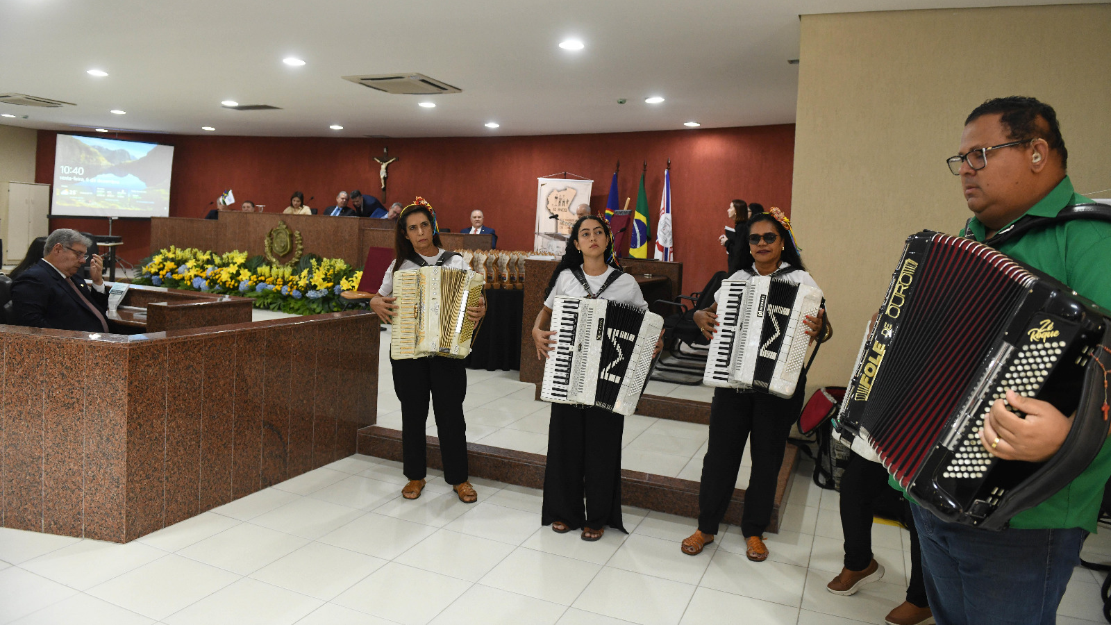 Um homem e duas mulheres sanfoneiras tocam juntos no fórum de Caruaru.