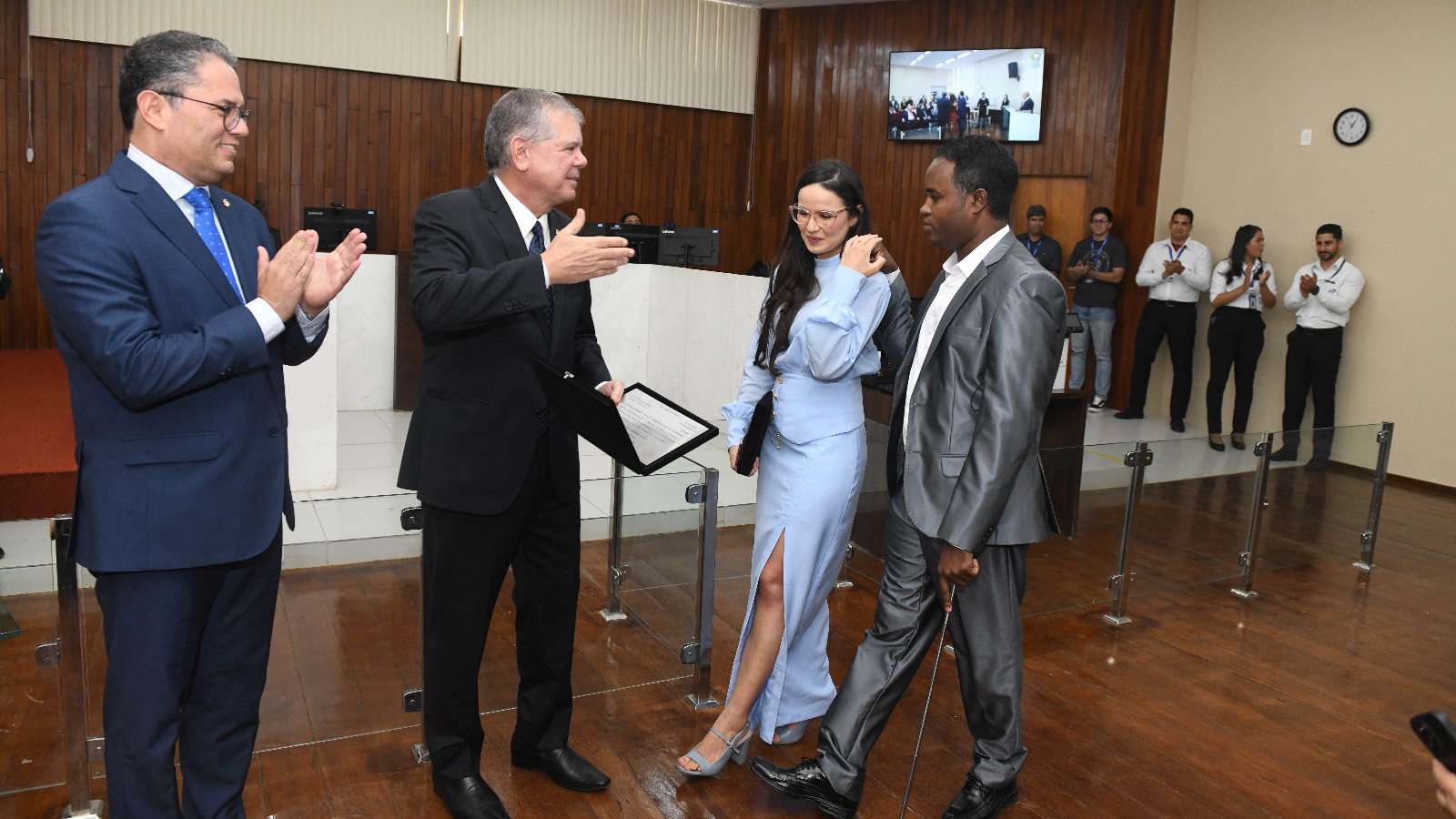 O presidente do TJPE recebe e presenteia um casal que vem até ele na sala de sessões.