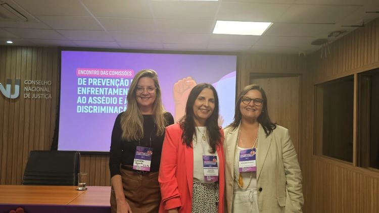 Luciana, Valéria e Ana Mota estão posando para foto em frente ao palco da apresentação.