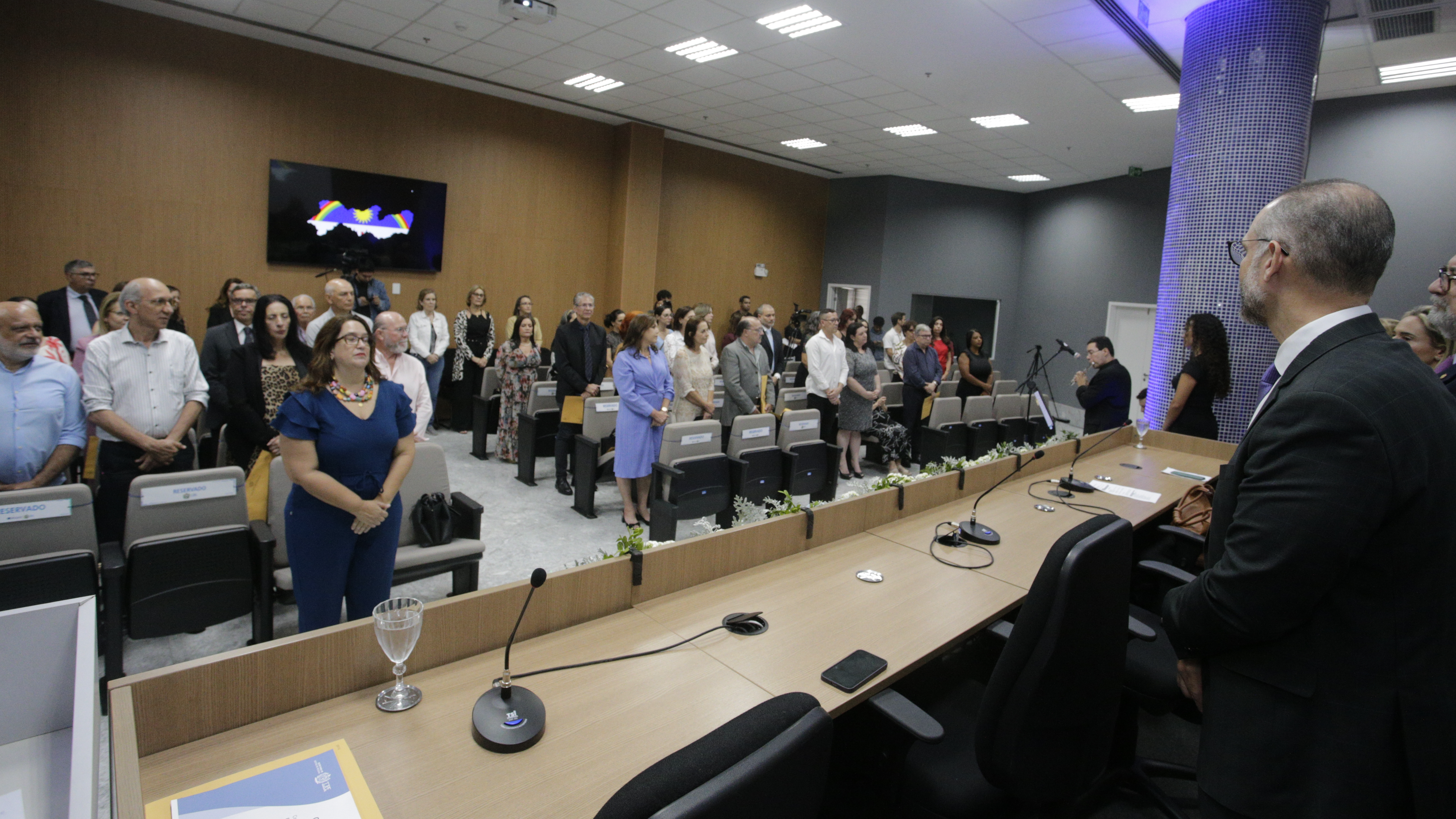 Foto do palco vendo a plateia repleta de servidores cantando o hino nacional.