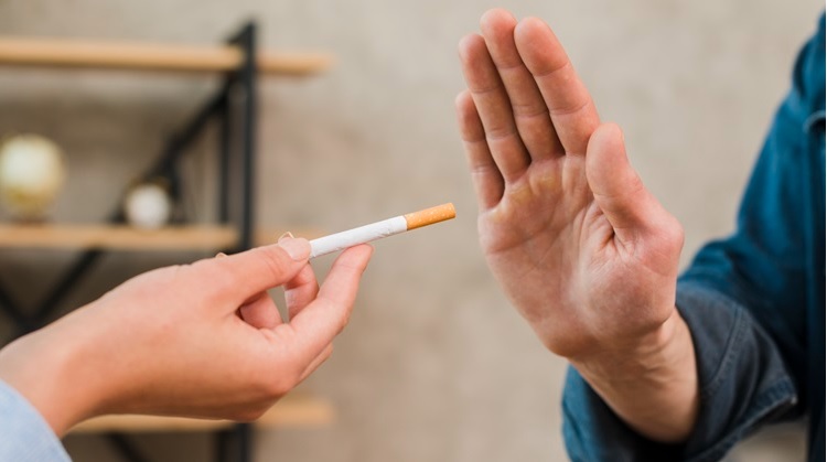 Uma pessoa fazendo sinal de pare para outra que está entregando cigarro